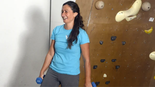 Isa, de Planet Vertical en Alcalá de Henares, riendo con unas pesas en las manos, a punto de empezar a explicar un ejercicio de la clase de fitness