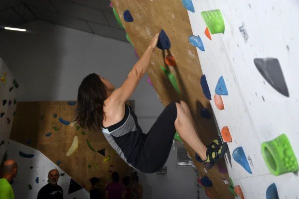 Mujer escalando, en una posición dinámica en un desplome del bloque en Planet Vertical, en Alcalá de Henares